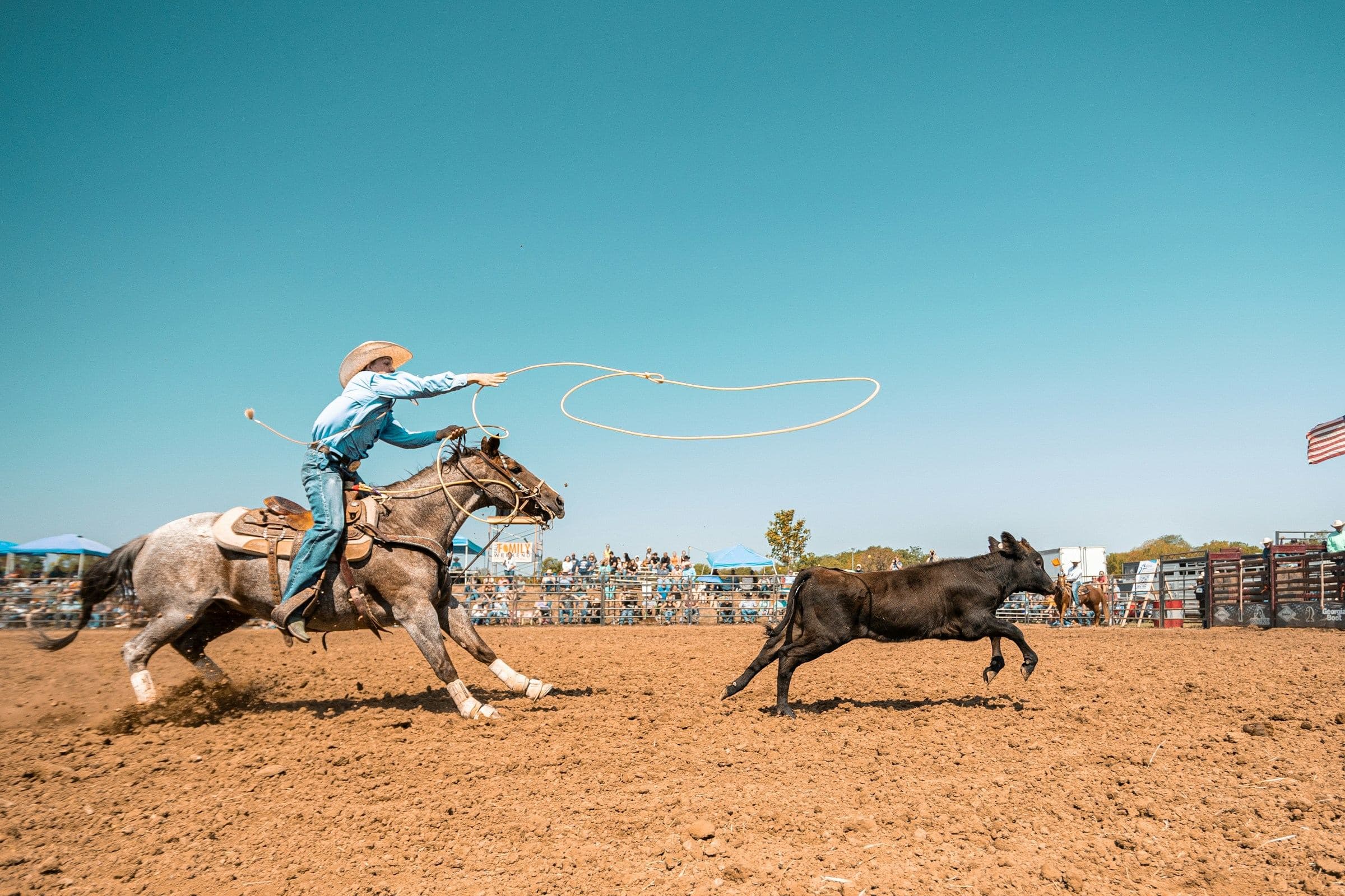 A roper leaning out of the saddle mid-swing in a dirt arena, with a trainer's red ring drawn around the seat and a note about sitting down.