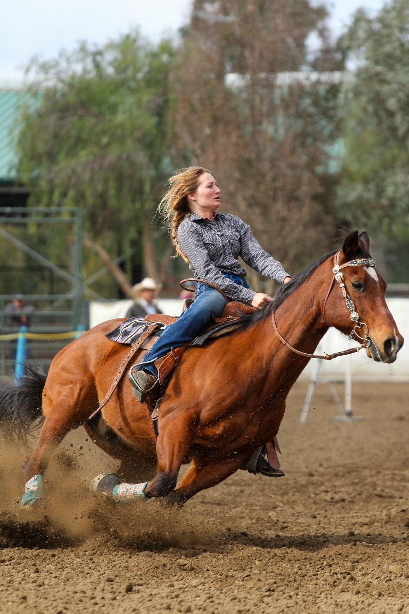 A barrel racer leaning into a turn, dirt flying from the horse's hooves.